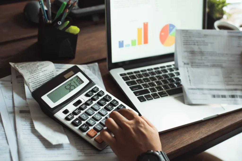 bilgisayar önünde belgeler ve hesap makinesi ile hesaplama